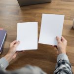 Dirigeante de TPE comparant deux offres de logiciel de paie, feuilles vierges