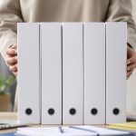 Dirigeante de TPE/PME alignant des classeurs représentant les étapes du processus de gestion de la paie